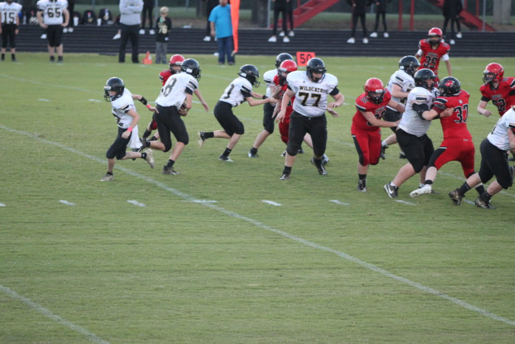 #12 Quarterback Brady Stooksberry hands the ball off to running back #18 Case Butler.